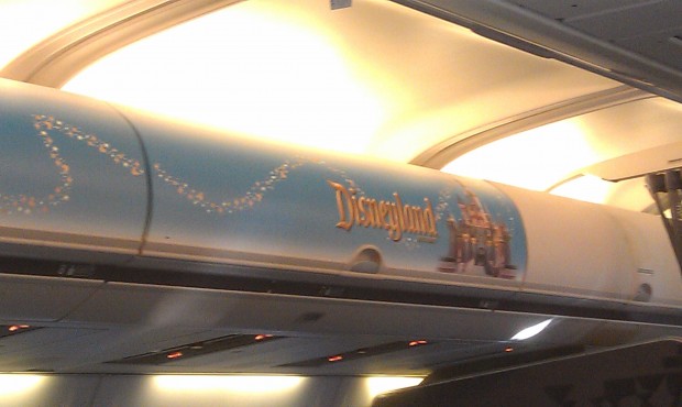 Onboard the plane a Disneyland sign on the overhead bin