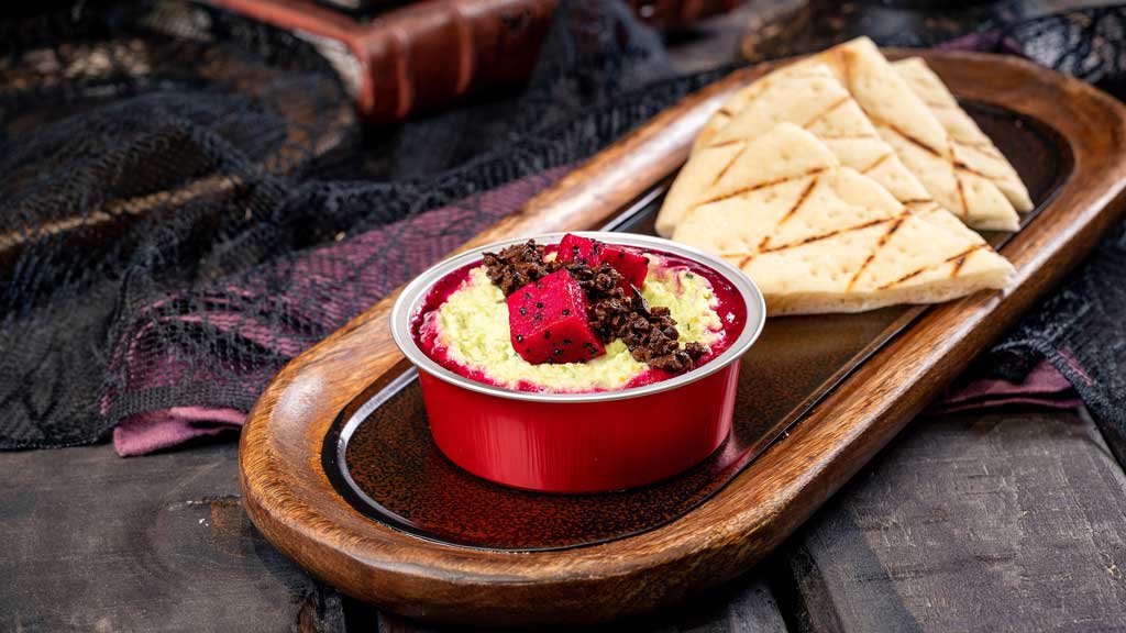 At Sonoma Terrace at Disney California Adventure Park, guests will find this Snake Eyes Sludge featuring edamame hummus dip with olive tapenade “bugs” and dragon fruit “dice” served with grilled flatbread triangles. (David Nguyen/Disneyland Resort)
