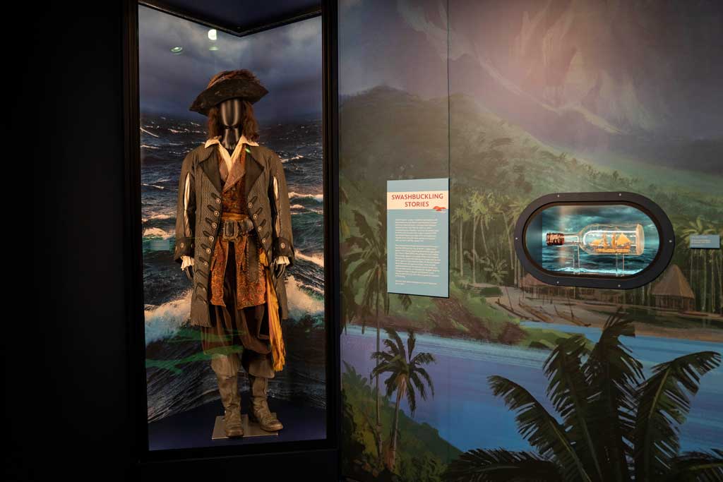 Captain Barbossa costume worn by Geoffrey Rush in Pirates of the Caribbean: The Curse of the Black Pearl (2003) and prop ship in a bottle from Pirates of the Caribbean: On Stranger Tides (2011) on display at Disney100: The Exhibition, now open at The Franklin Institute in Philadelphia. ©Disney