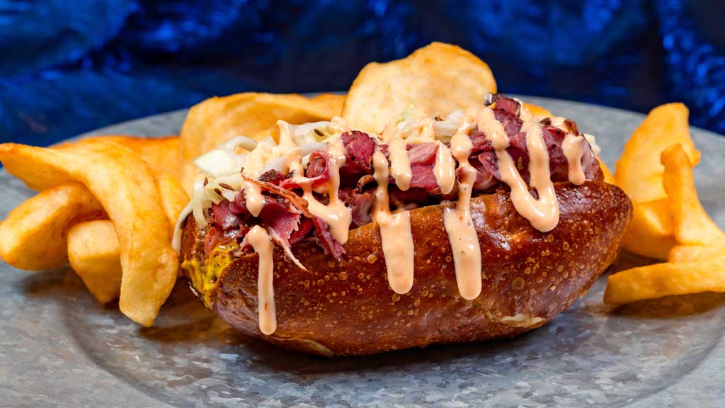 Pastrami Pretzel Dog at Award Wieners: All-beef hot dog topped with pastrami, whole-grain mustard, provolone, sauerkraut, and thousand island dressing