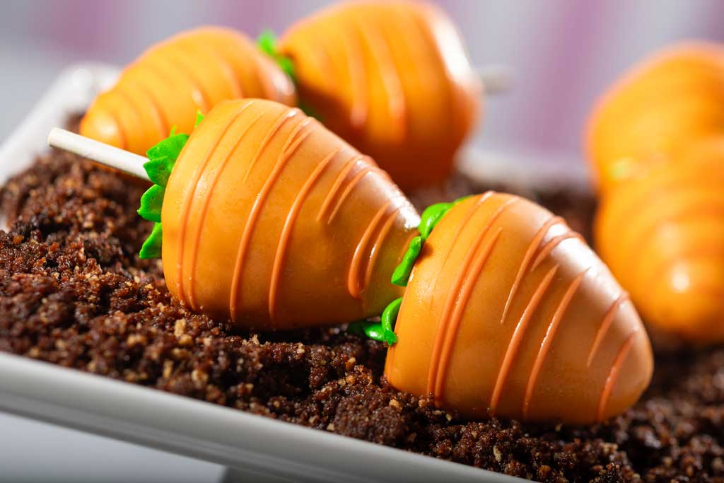 A crop of three Carrot Chocolate Covered Strawberries will be served over cookie crumble soil and decorated with piped stems made of frosting. (Kent Phillips, Photographer)