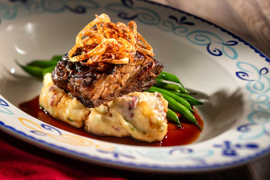 At Plaza de Coco, an array of artful dishes will transport guests to the picturesque town depicted in the Pixar Animation Studios film, “Coco.” Enrique's Port Wine Braised Center Cut Beef Short Rib will include cheddar cheese, a green onion red mash and long green beans with crisp shallots. (Kent Phillips, Photographer)