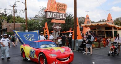 Lightning McQueen and the other residents of Radiator Springs are celebrating Haul-O-Ween. He is dressed as a super hero for Trunk or Treating. Here he is rolling along Route 66 by the Cozy Cone in Cars Land.