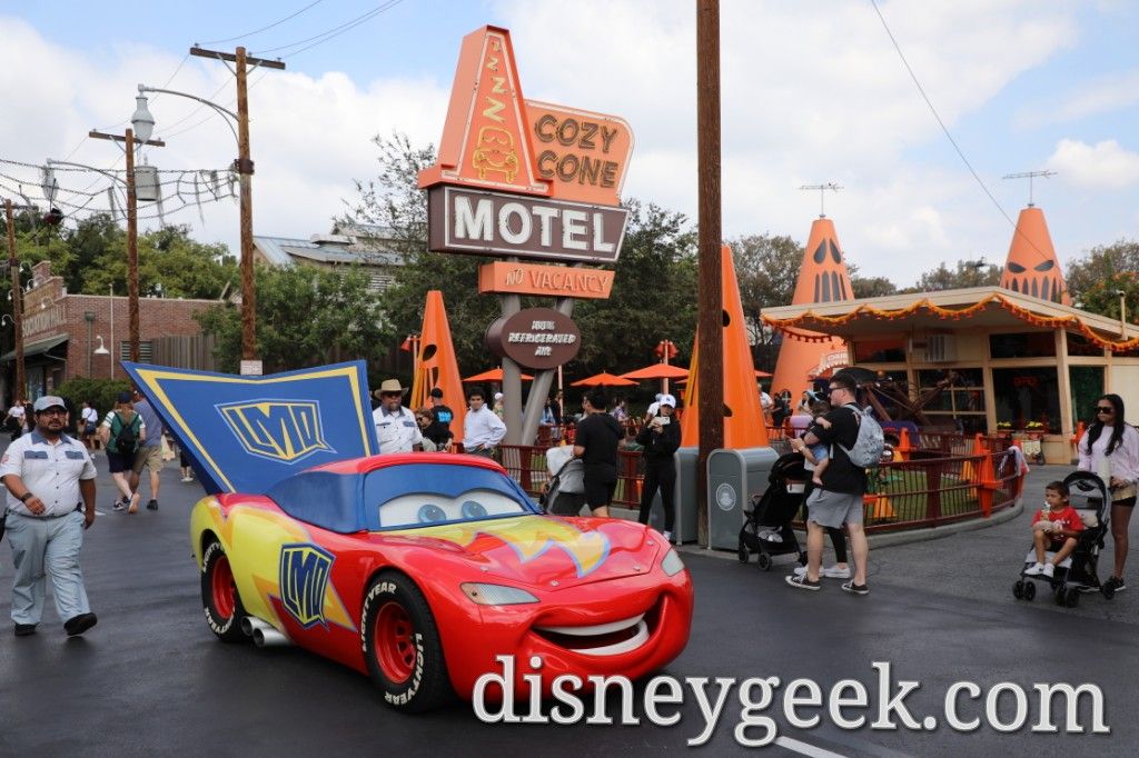 Lightning McQueen and the other residents of Radiator Springs are celebrating Haul-O-Ween.  He is dressed as a super hero for Trunk or Treating.  Here he is rolling along Route 66 by the Cozy Cone in Cars Land.

